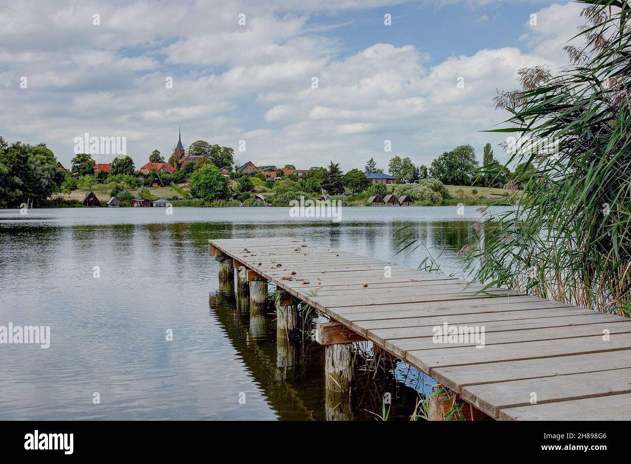 Idyllic on the southwestern shore of lake Plätlinsee lies the small village Wustrow. On the hill above the lake rises since 1896 a brick church. Stock Photo
