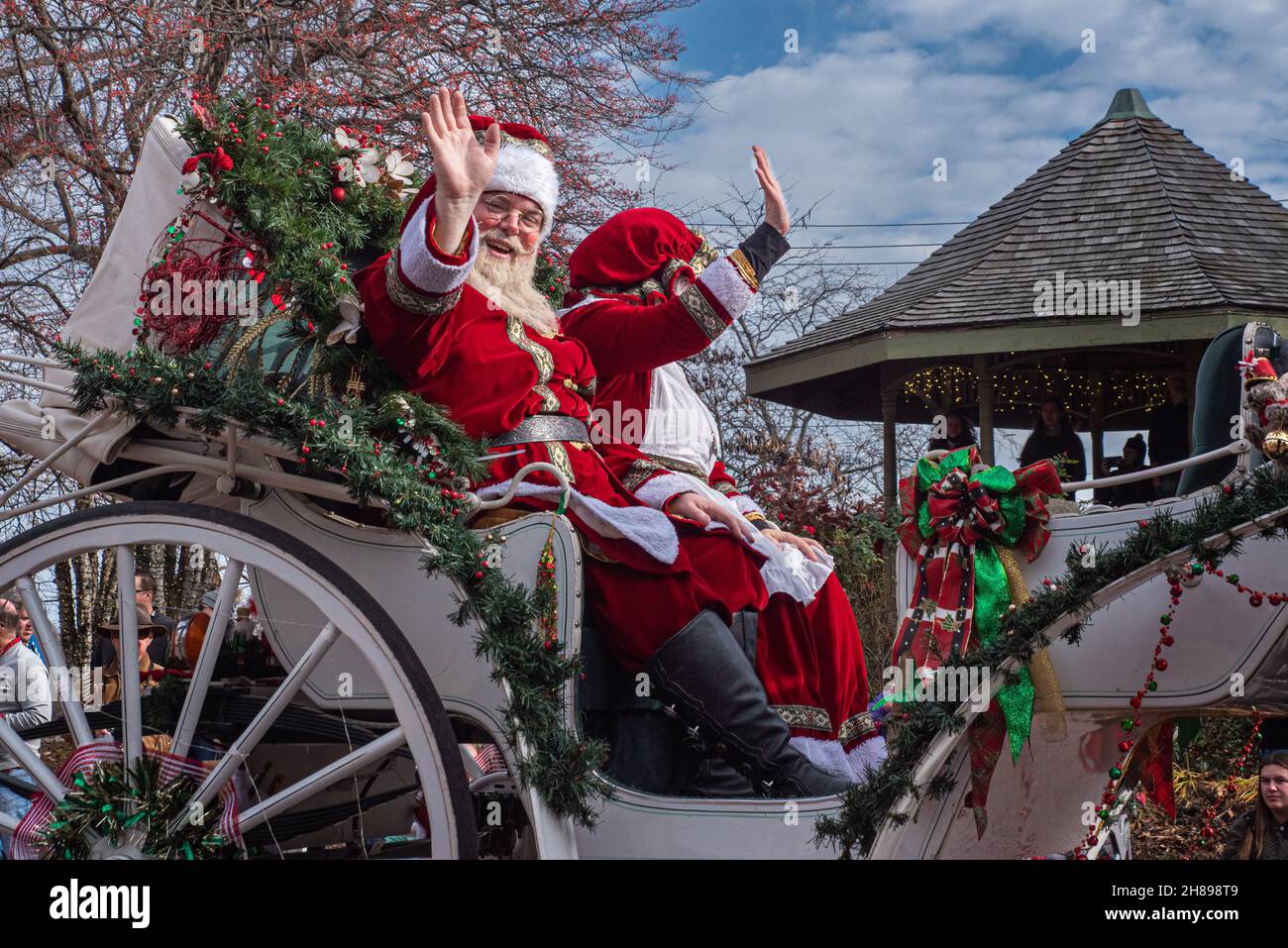 St. Charles, MO—Dec 27, 2021; actor and actress portray Santa and Mrs Claus while waving two crowds form a horse drawn carriage in downtown Christmas Stock Photo