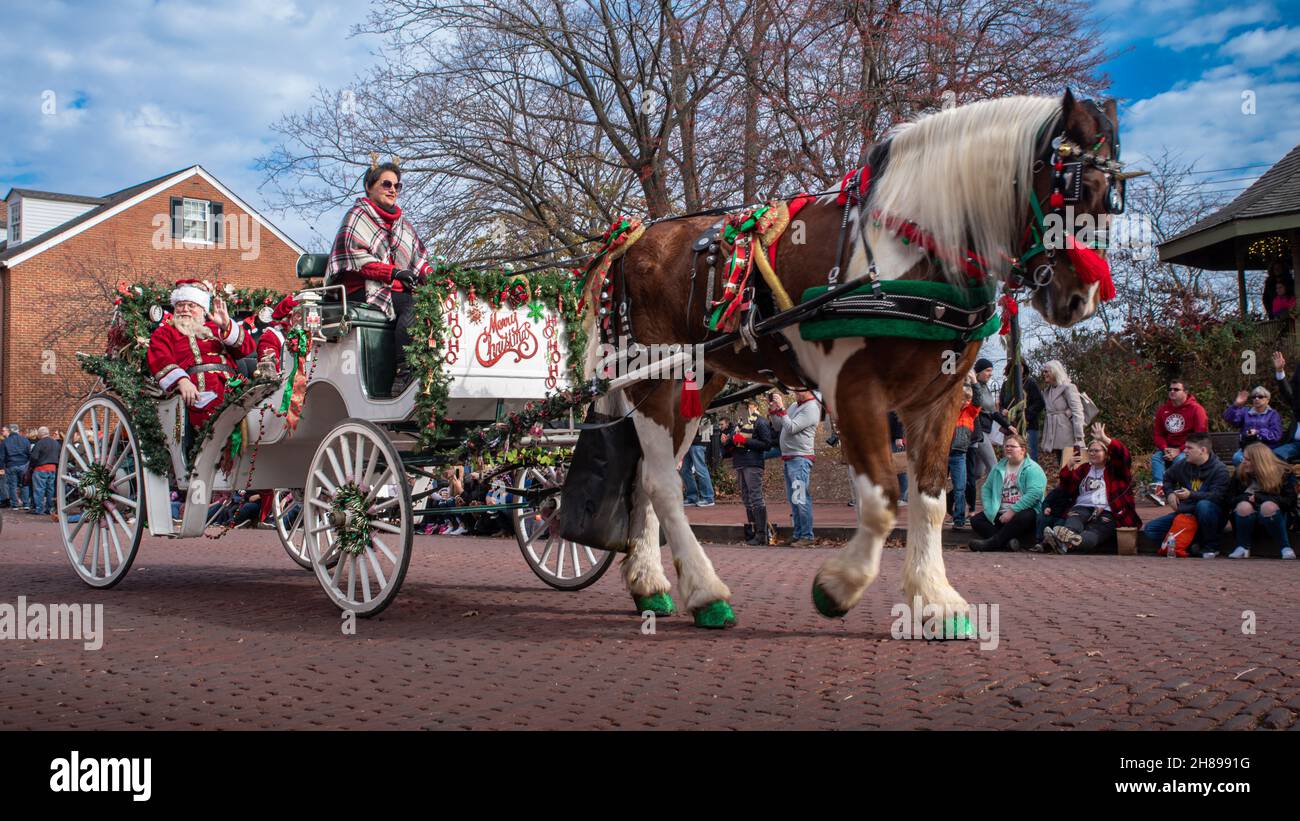 St. Charles, MO—Dec 27, 2021; actor and actress portray Santa and Mrs Claus while waving two crowds from a horse drawn carriage in downtown Christmas Stock Photo