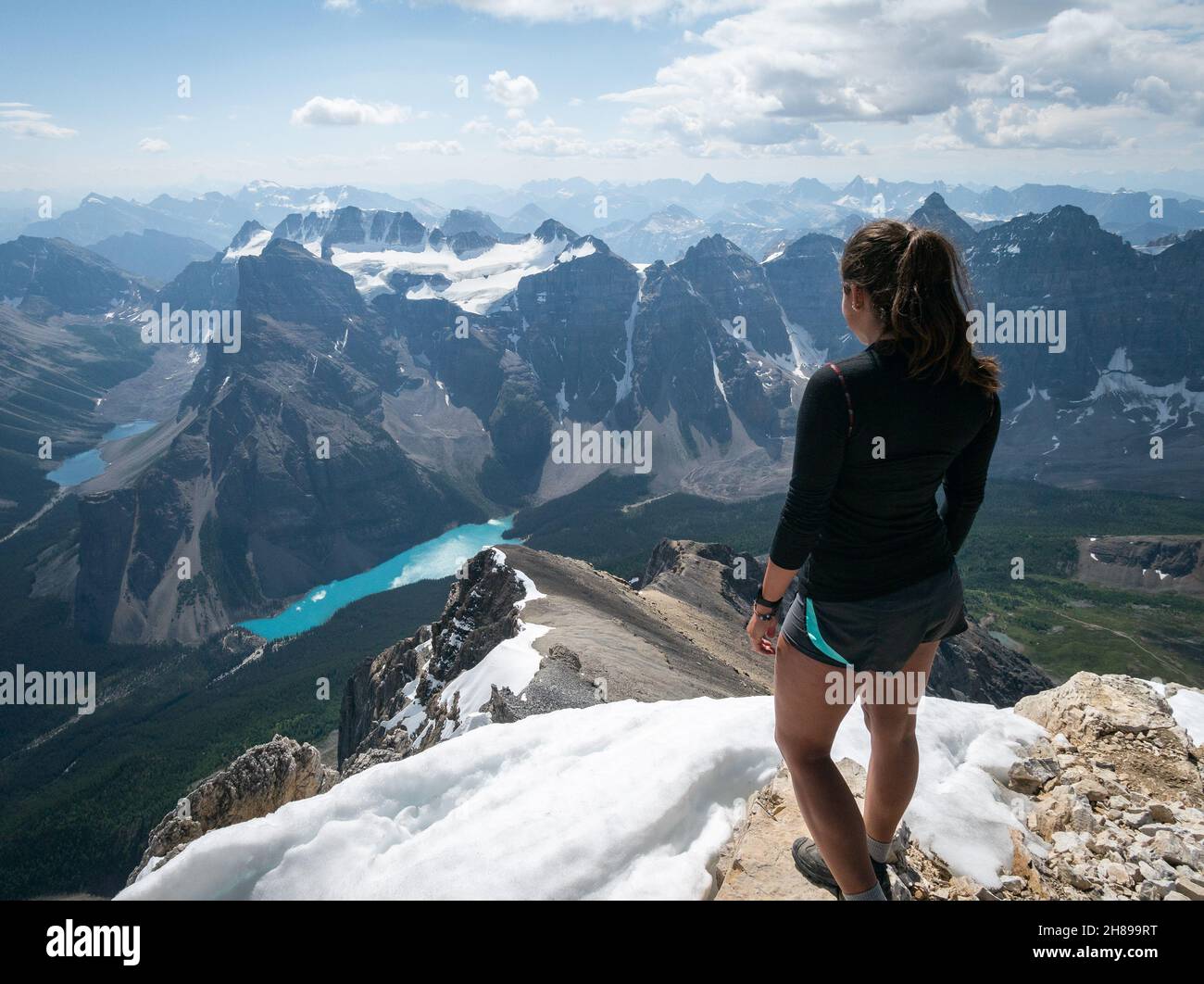 Female hiker looking on Moraine Lake from summit of Mount Temple, Banff, Canadian Rockies, Canada Stock Photo