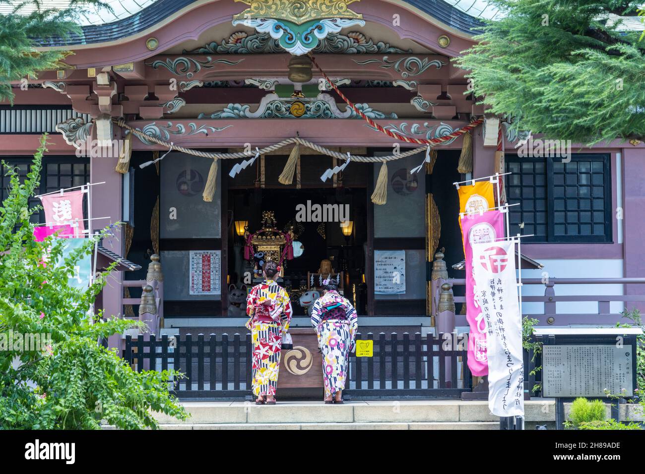 Japanese women dressed in kimono offer prayers at the Imado Jinja Shrine, a Shinto shrine dedicated finding love in Asakusa, Tokyo, Japan. The temple is known for the “Maneki Neko” or the “Beckoning Lucky Cat” figurines. Stock Photo