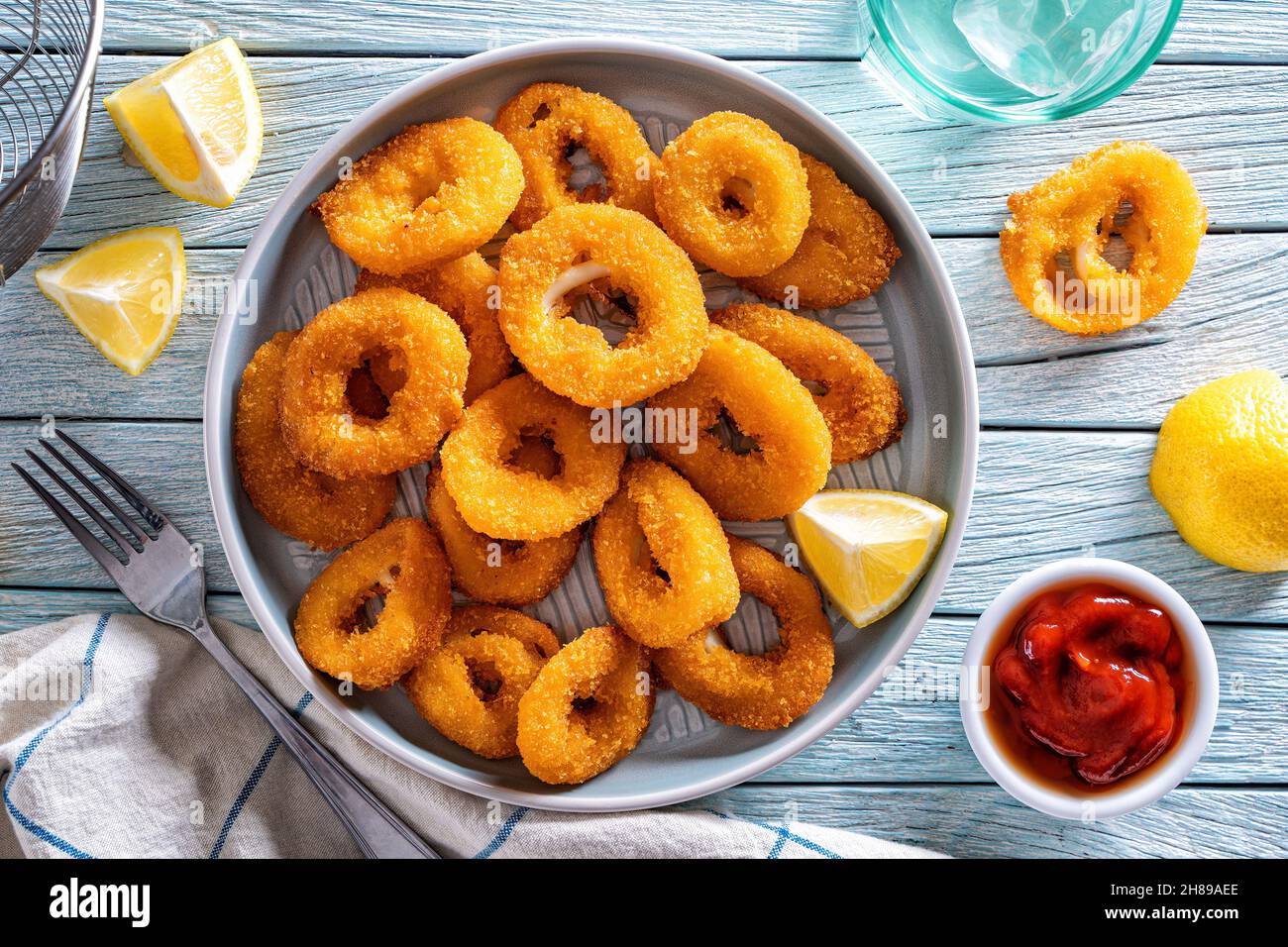 Delicious crispy breaded and fried calamari with lemon and seafood sauce. Stock Photo