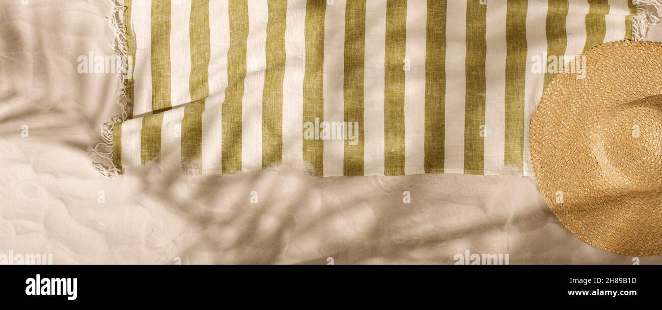 Striped linen beach towel with fringes and straw hat on sandy beach ...