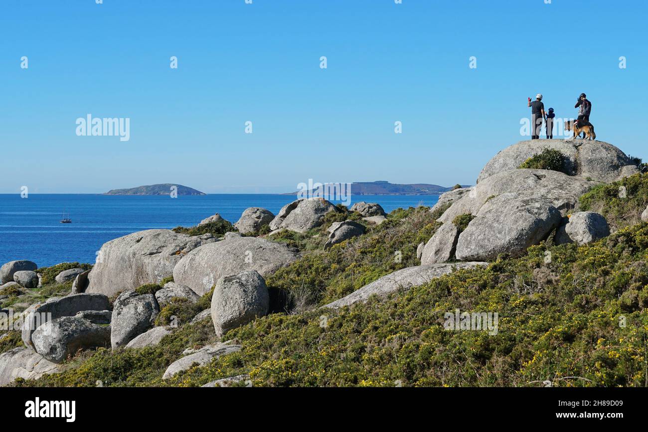 Spain, Galicia, coastal landscape with people on top of boulders rocks ,Cape Udra, Atlantic coast, Bueu, Pontevedra province Stock Photo