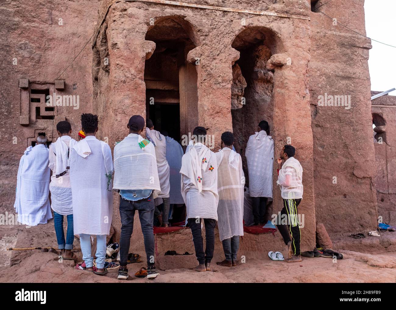 Lalibela, Ethiopia - May 23, 2021: Parishioners attending a mass from outside a church and wearing white clothing over their usual cloths Stock Photo