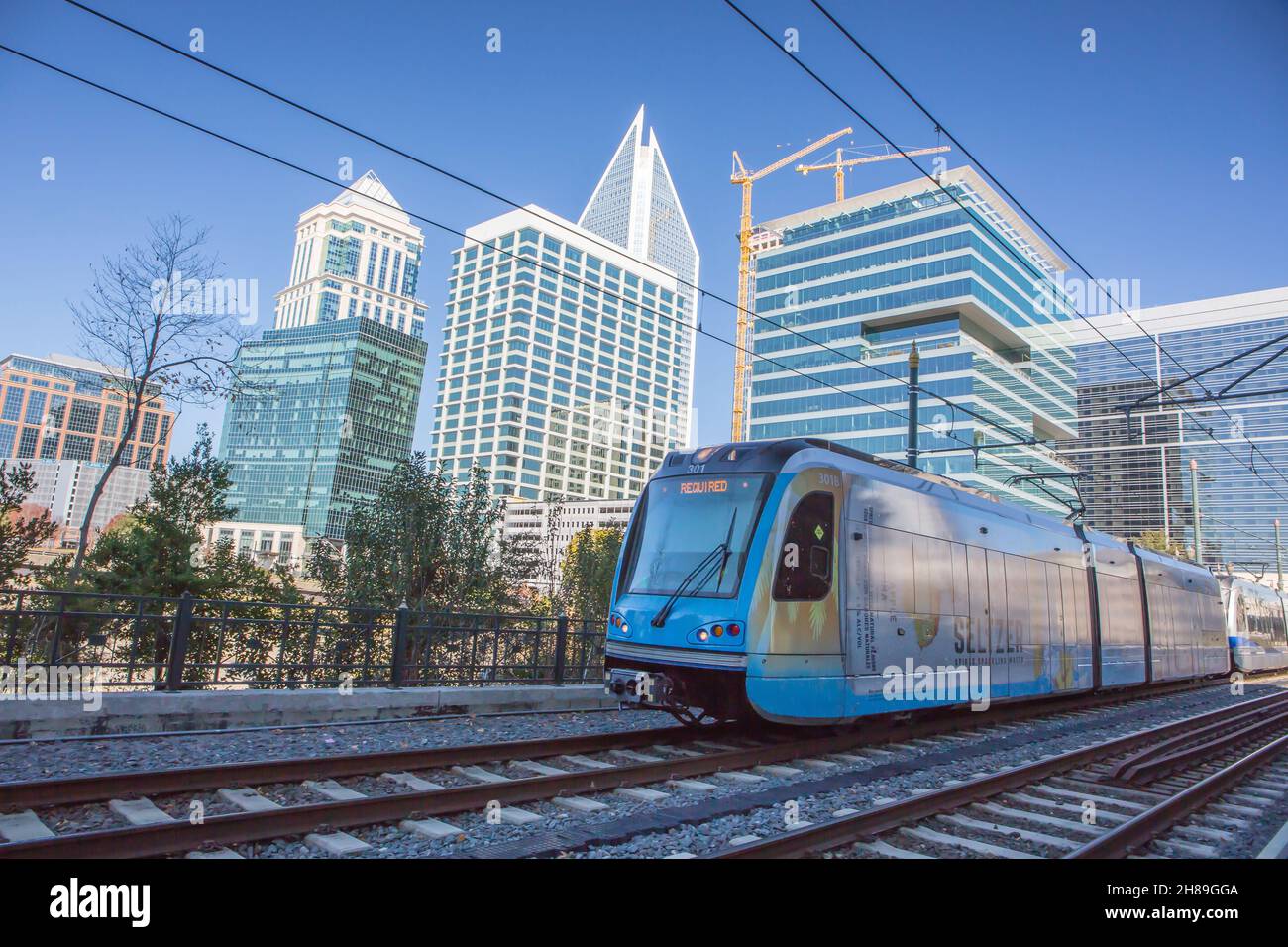 A light rail commuter train in Charlotte, North Carolina, with the uptown skyline in the background. Stock Photo