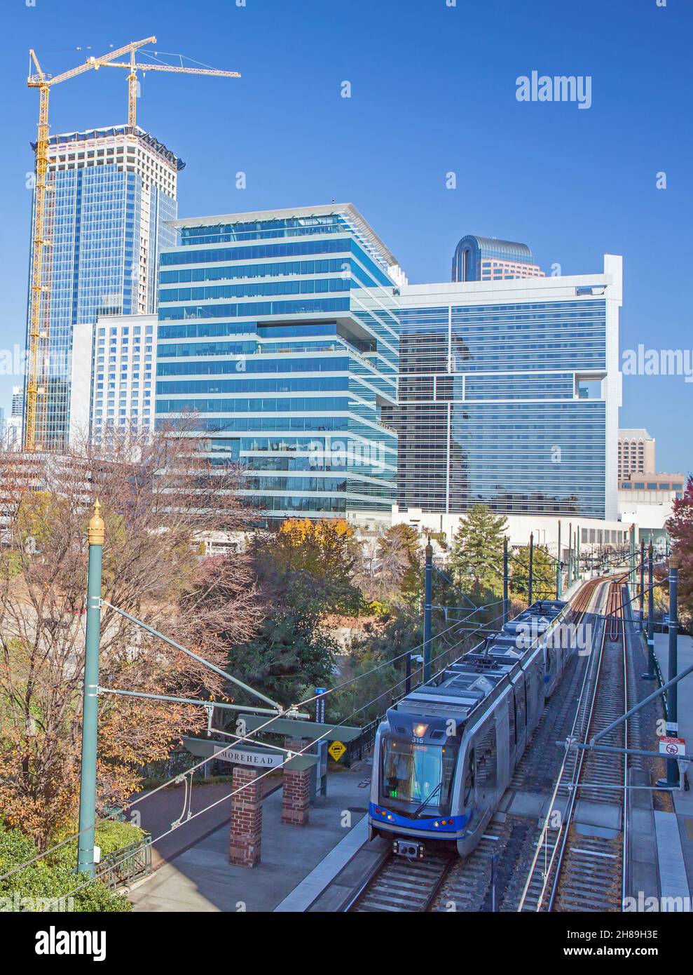 A light rail commuter train in Charlotte, North Carolina, with the uptown skyline in the background. Stock Photo