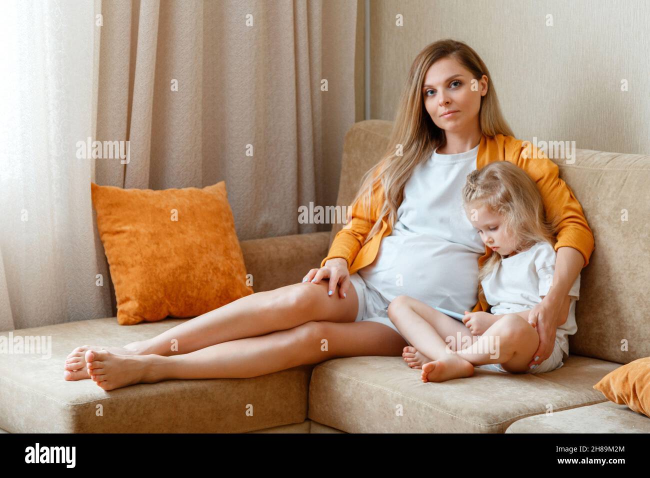 Little girl child kid 5 years old use phone with mom sitting on couch at home. Mother and daughter portrait while spend leisure time together Watching Stock Photo