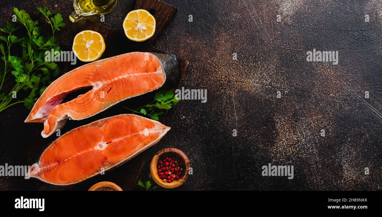 Steaks of chum salmon raw with spices, herbs, salt and lemon on old stone background. Top view copy space. Stock Photo