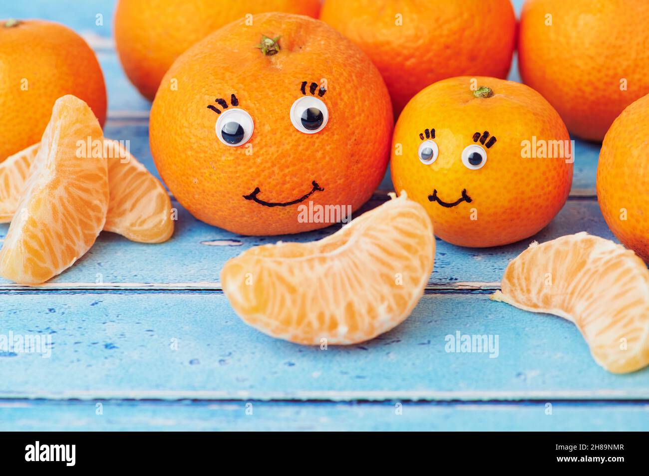 tangerines with funny faces on blue background Stock Photo