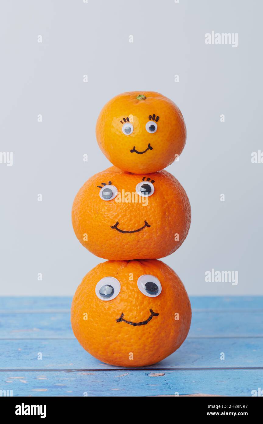 three tangerines with funny faces on each other Stock Photo