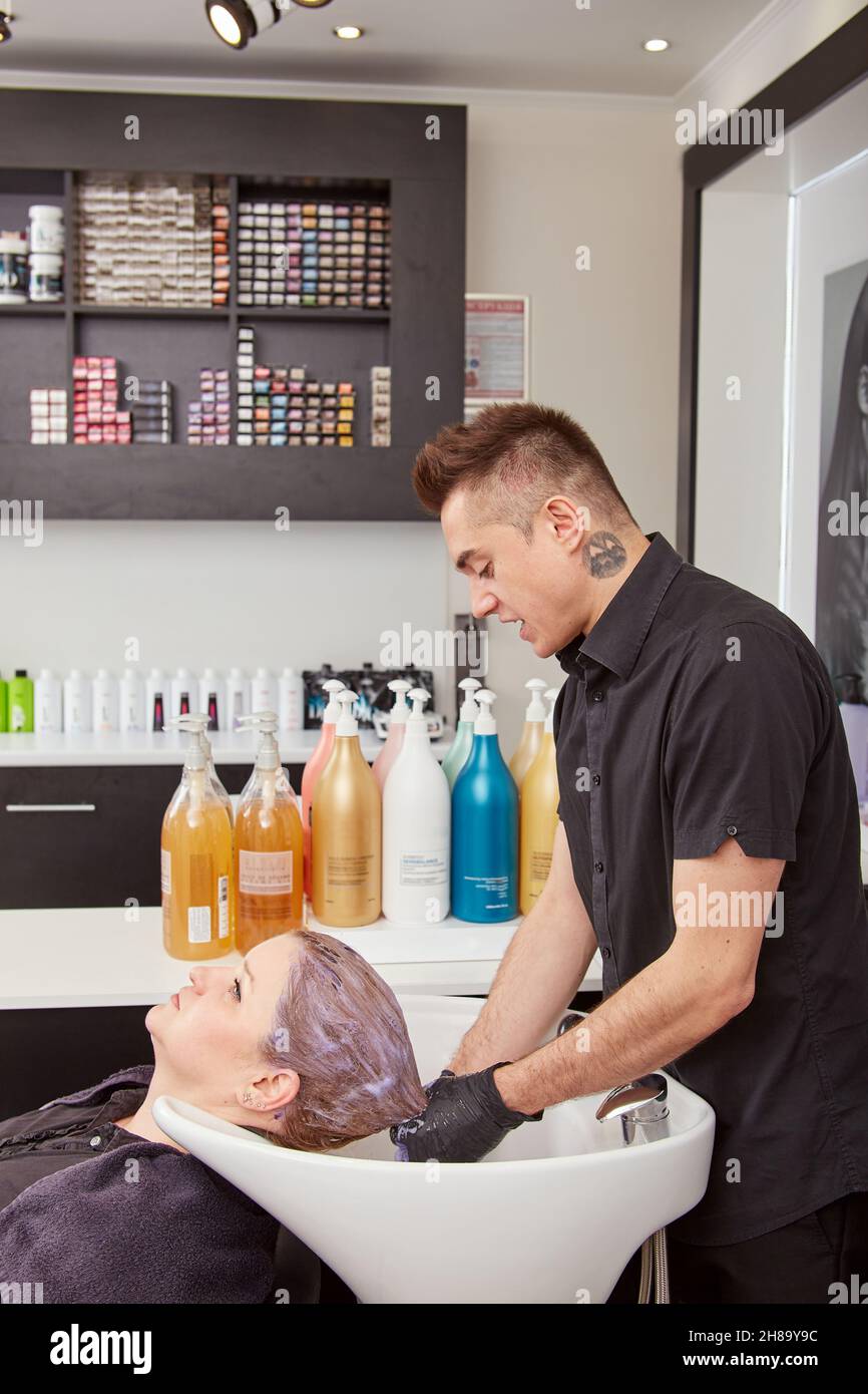 Handsome hairdresser toning client hair in salon Stock Photo - Alamy