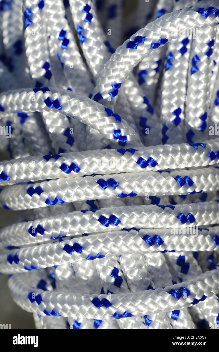 Close up and detailed view of a coiled plastic rope with white and blue fibers Stock Photo