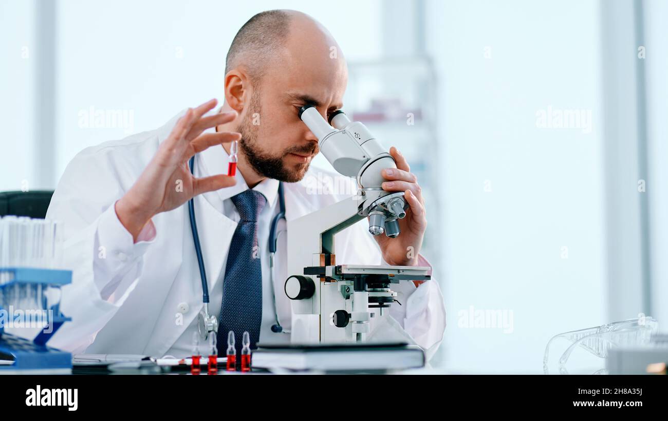 close-up. scientist studying vaccine samples through a microscope . Stock Photo