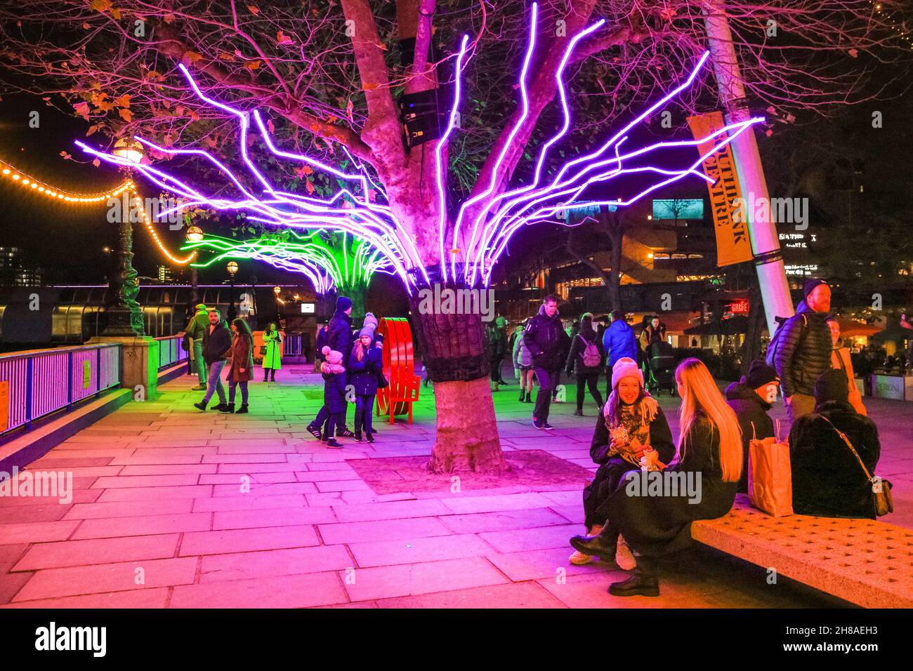 London, UK. 28th Nov, 2021. Londoners sit and stroll along the neon illuminated tree canopies that are part of the Southbank Winter Lights this year. The free display can be seen every day from dusk until 11.30pm, until January 9th, 2022. Credit: Imageplotter/Alamy Live News Stock Photo