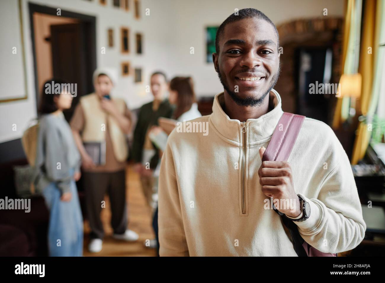 Portrait of African happy man with backpack behind his back smiling at camera while standing at university Stock Photo
