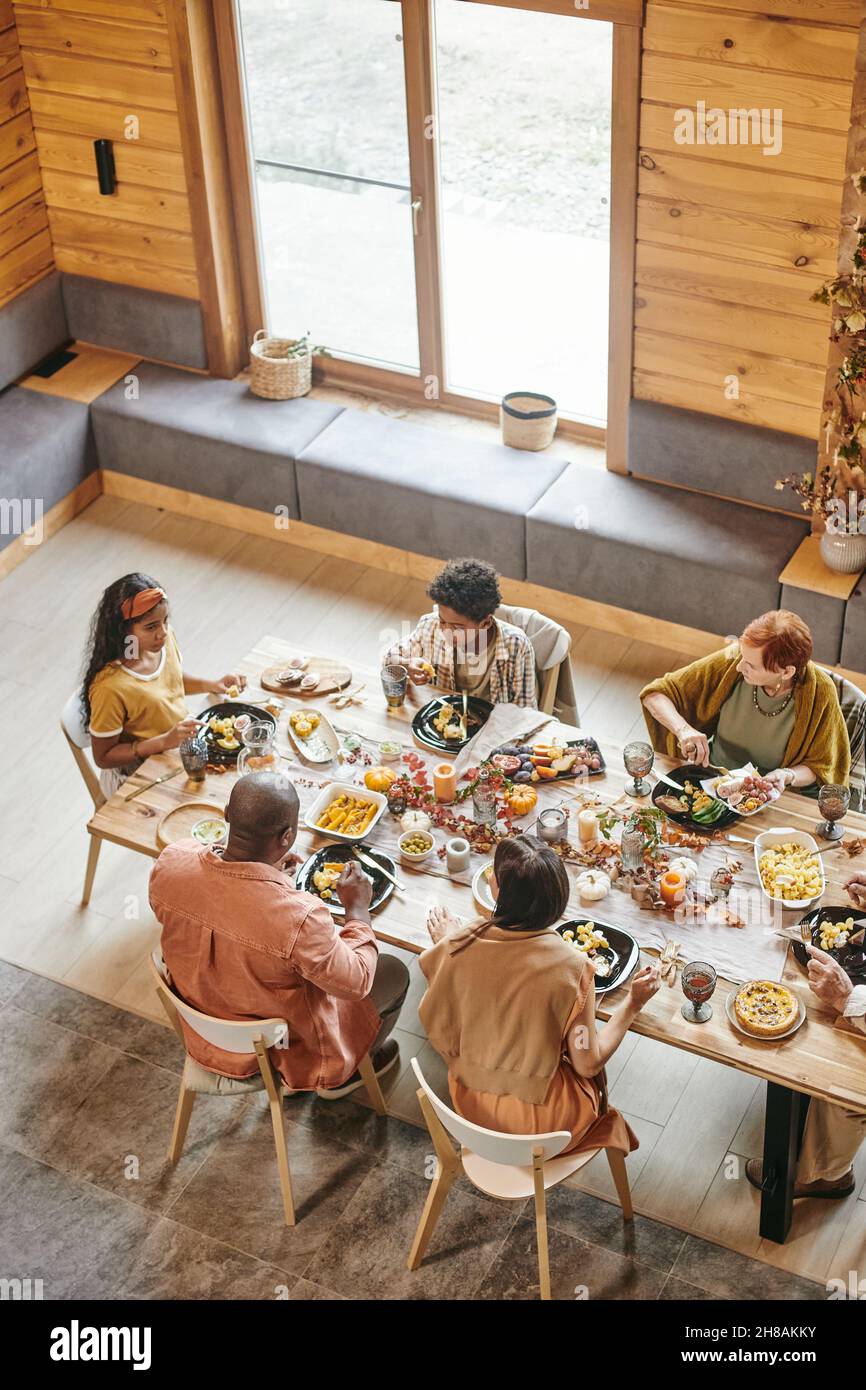 Contemporary family of five people having festive dinner by large table