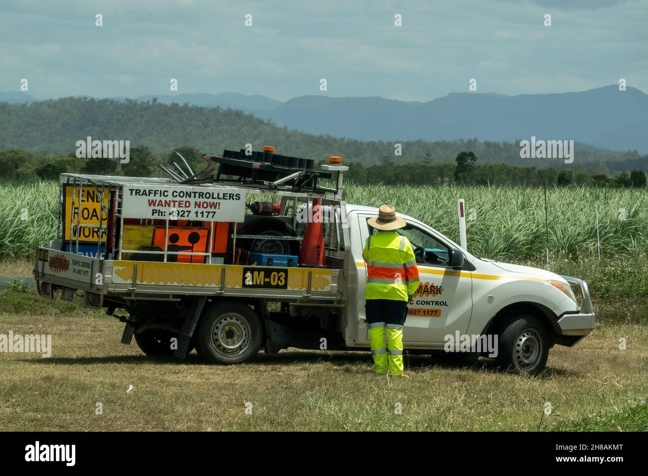 Bruce Highway, Townsville to Mackay, Queensland, Australia - November 2021: Traffic controller vehicle with worker on roadside in front of sugarcane c Stock Photo