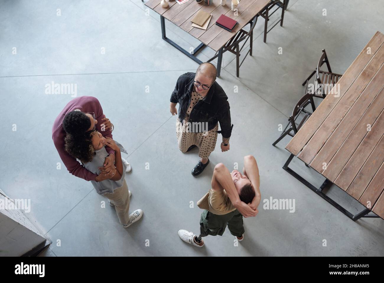 Overview of happy co-workers enjoying break while two of them embracing, man with leg prosthesis exercising and young female looking at him Stock Photo