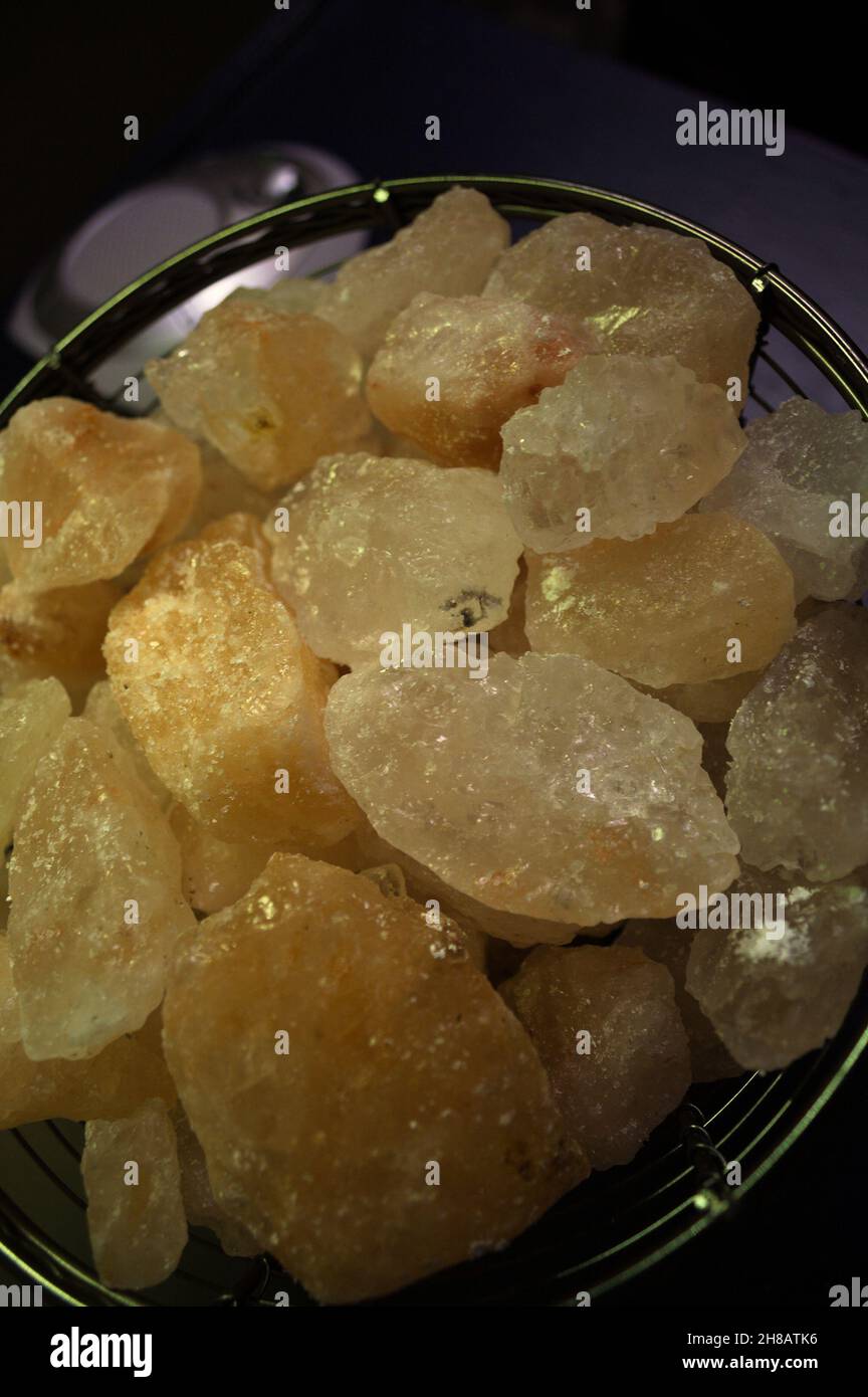 A calming glow emits from varying shapes and sizes of colorful salt crystals in a wire bowl. Stock Photo