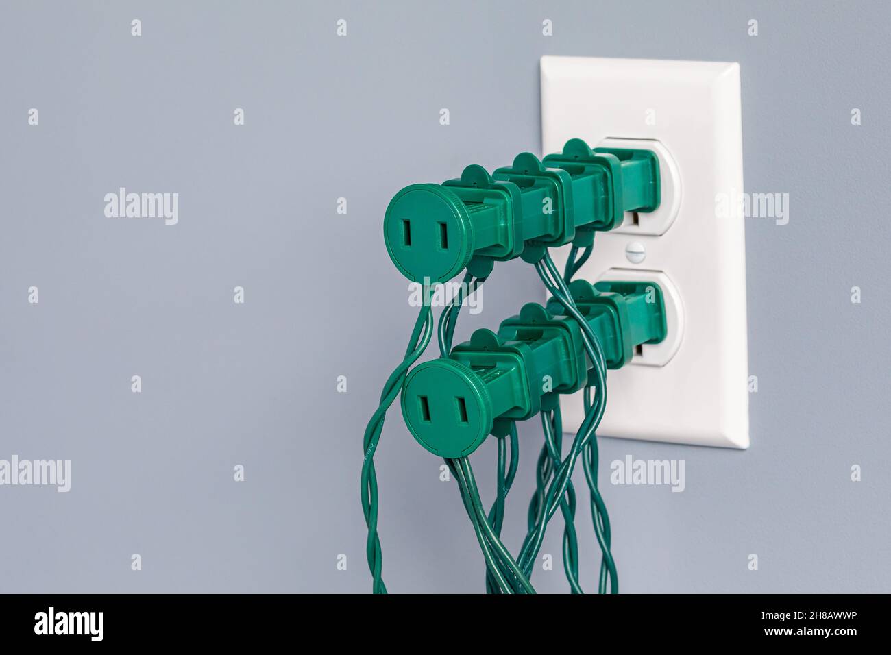 Electrical outlet overloaded with Christmas string lights. Holiday decoration safety, hazards and fire prevention concept. Stock Photo