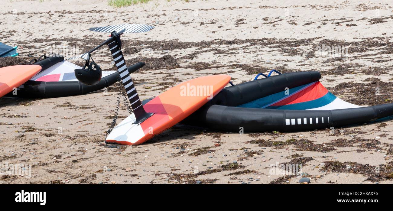 Kite surfing equipment lying on a beach surrounded by seaweed in