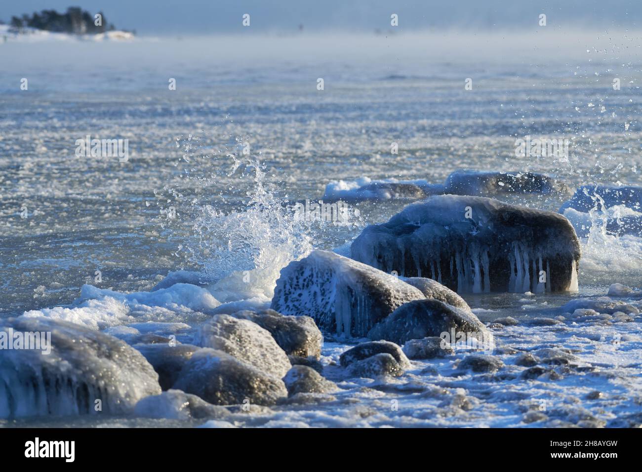 Ice covered rock by the Baltic Sea that about to freeze over with water splashing against the rocks in Helsinki, Finland on 14 January 2021. Stock Photo