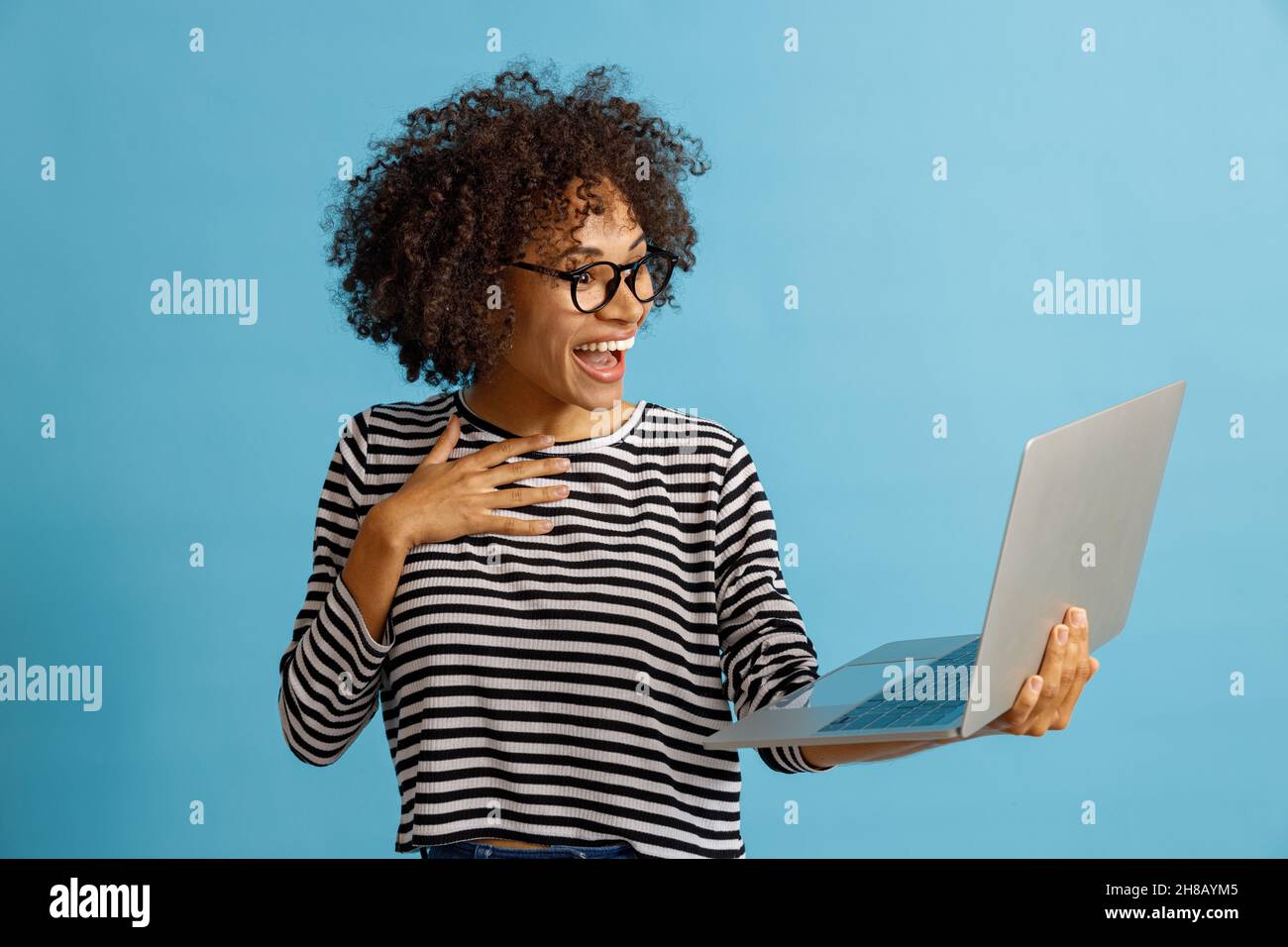 Happy young woman using notebook in studio Stock Photo
