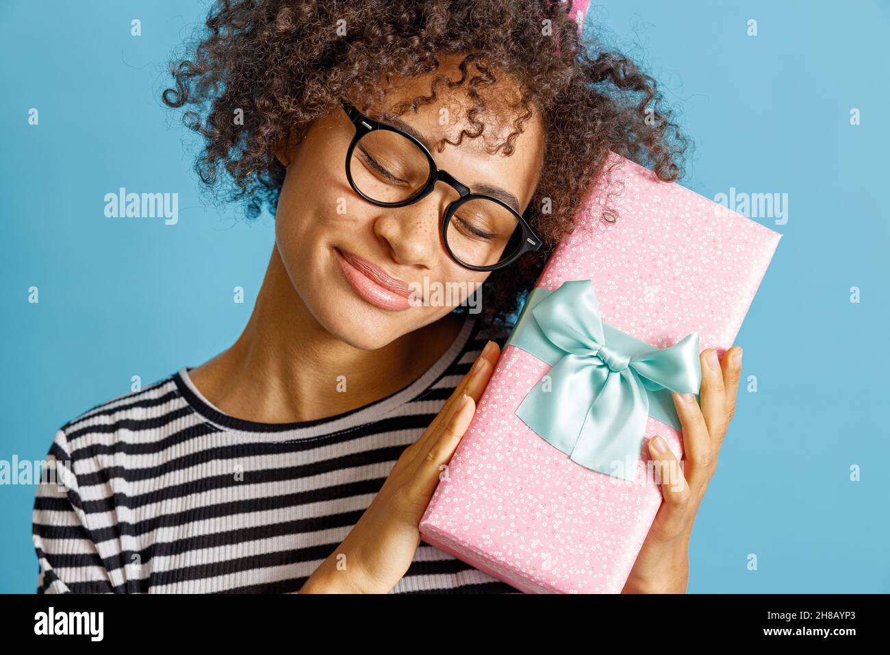 Joyful African woman holding gift box with ribbon Stock Photo