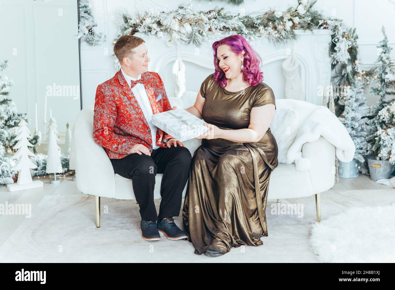 LGBTQ lesbian couple celebrating Christmas New Year winter holiday. Gay female with butch partner giving gift boxes with presents to each other on Chr Stock Photo