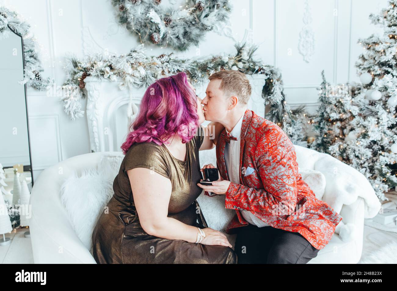 Homosexual gay butch woman proposing her girlfriend to marry her and giving her box with ring. LGBTQ lesbian couple celebrating Christmas or New Year Stock Photo