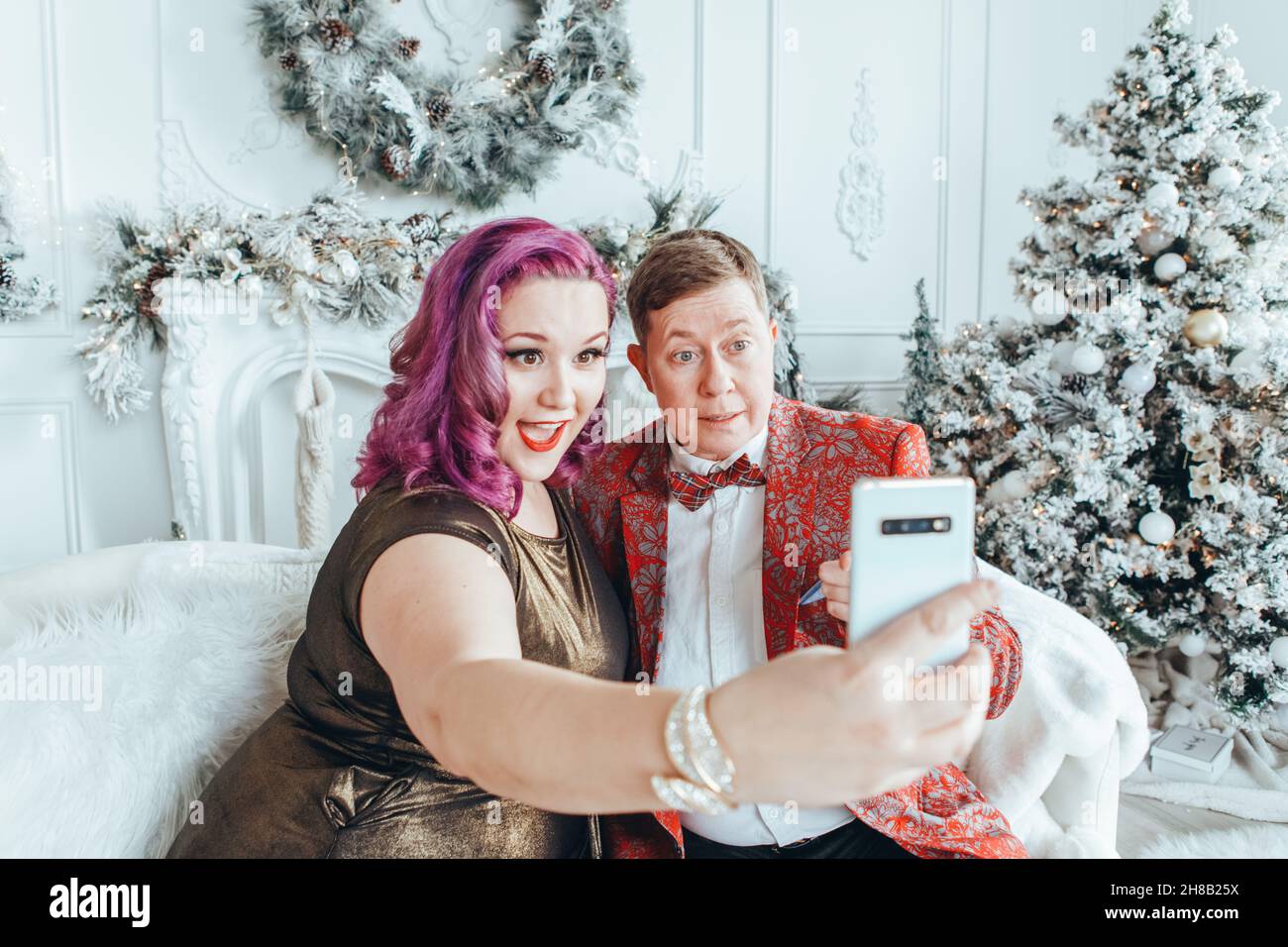 LGBTQ lesbian homosexual couple celebrating Christmas or New Year. Gay young lady female woman with butch partner taking selfie or chatting on phone i Stock Photo