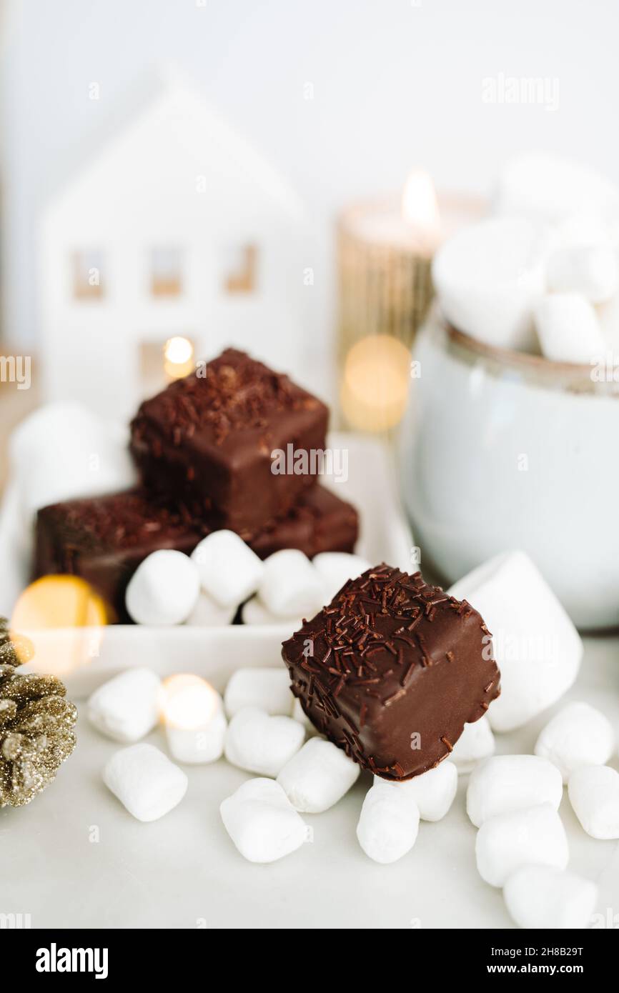 Dark Chocolate Petit Fours on White Background with Marshmallows, Mug, Bokeh Stock Photo