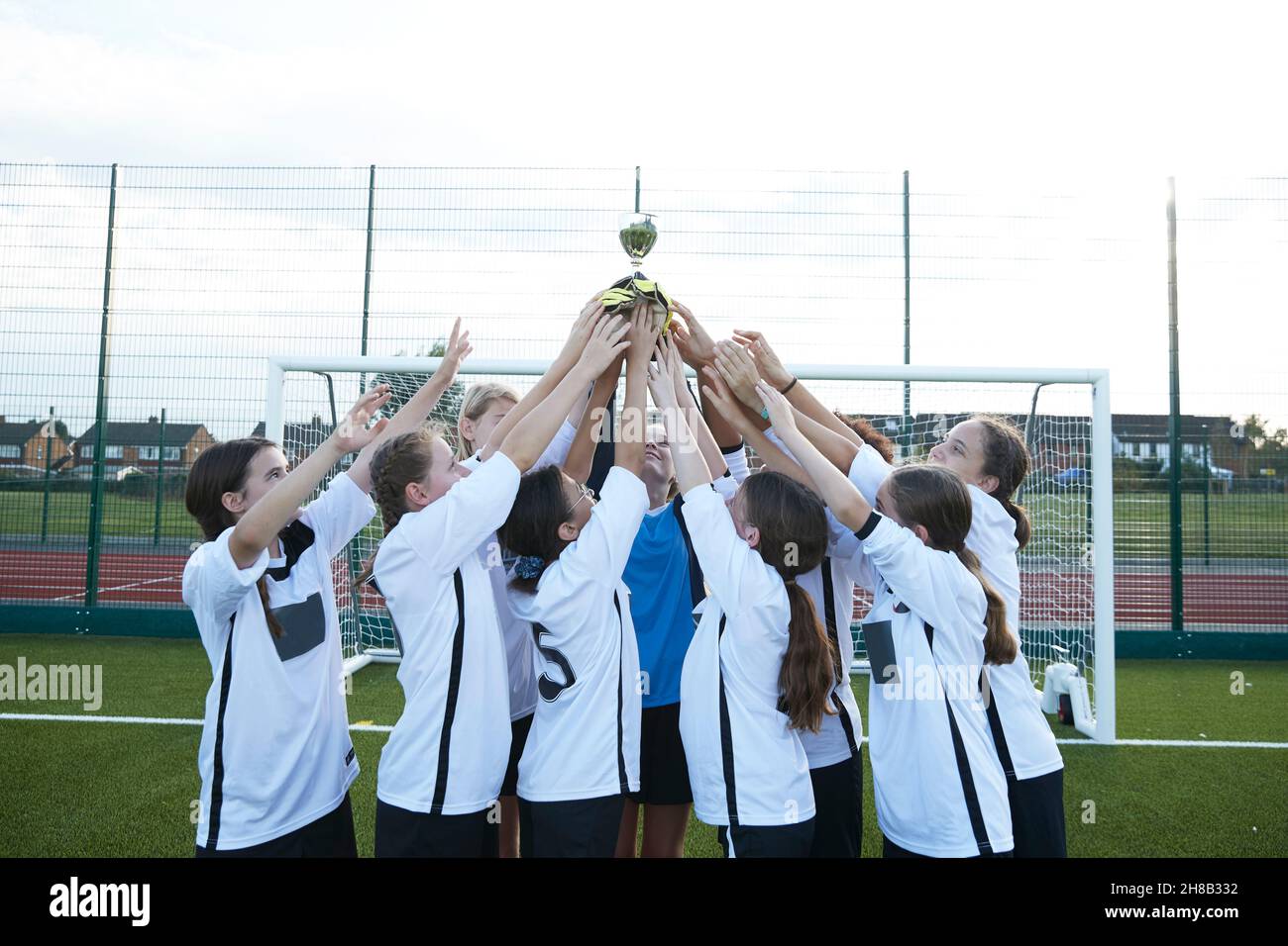 UK, Girls soccer team (10-11, 12-13) holding trophy in soccer field Stock Photo