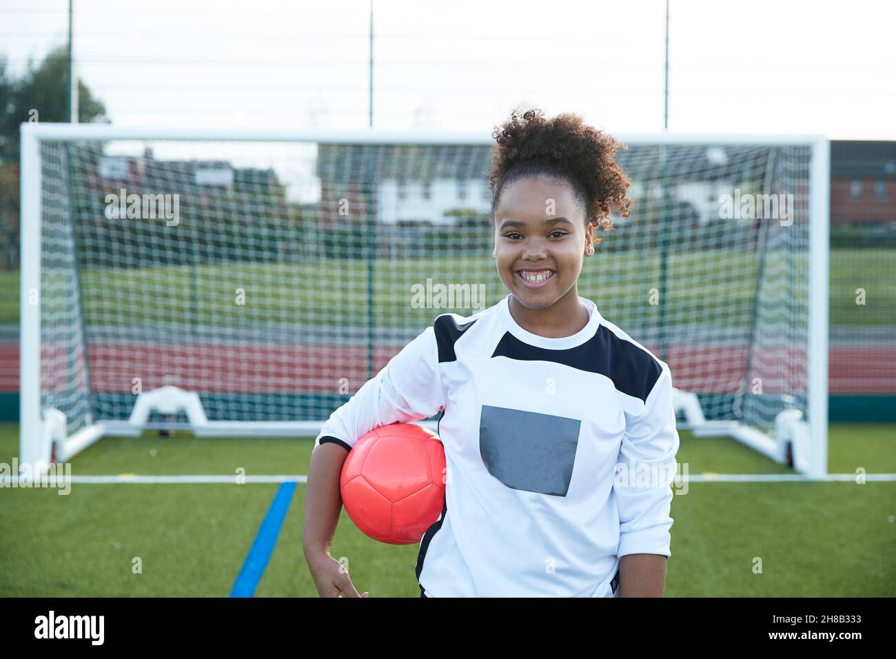 UK, Portrait of smiling female soccer player (12-13) in front of goal Stock Photo