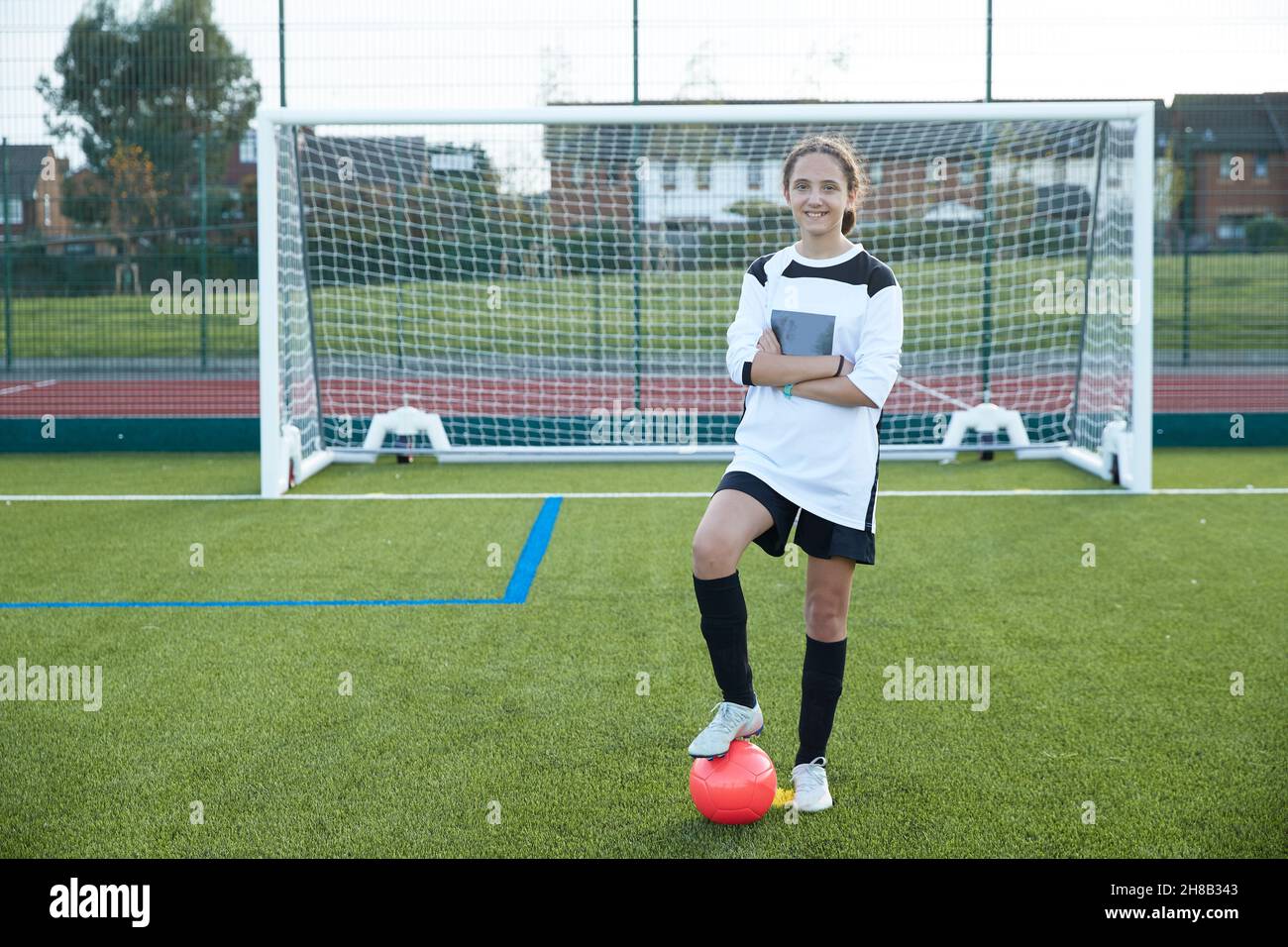 UK, Portrait of smiling female soccer player (12-13) in front of goal Stock Photo