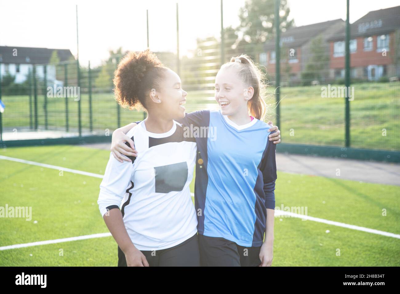 UK, Smiling female soccer team members embracing in field Stock Photo