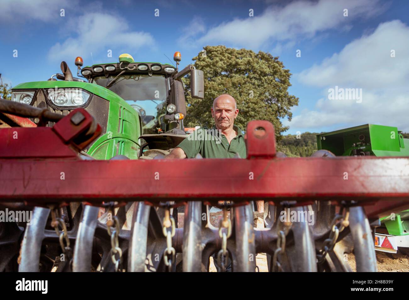 Portrait of farmer at tractor with cultivating plough in field Stock Photo