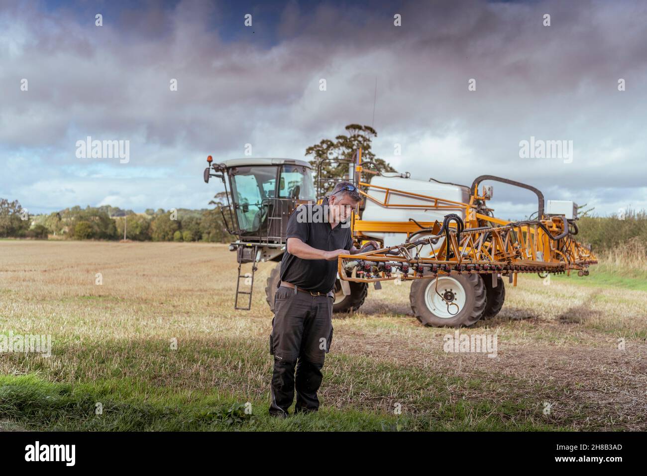 Farmer and agricultural machinery in field Stock Photo
