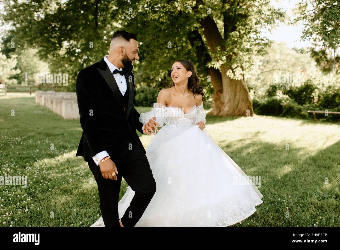 Happy bride and groom holding hands in park Stock Photo - Alamy