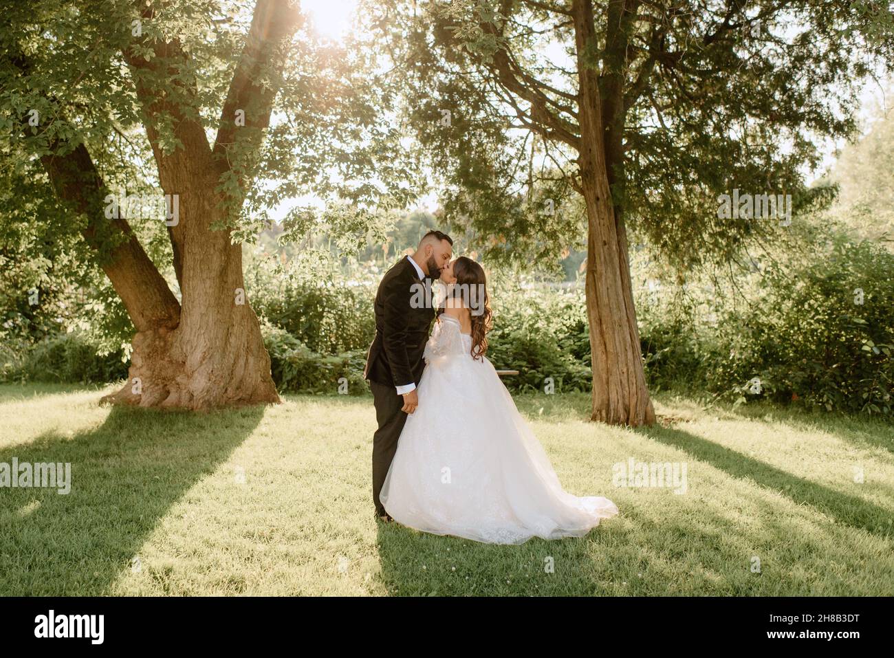 Bride and groom kissing in park Stock Photo - Alamy
