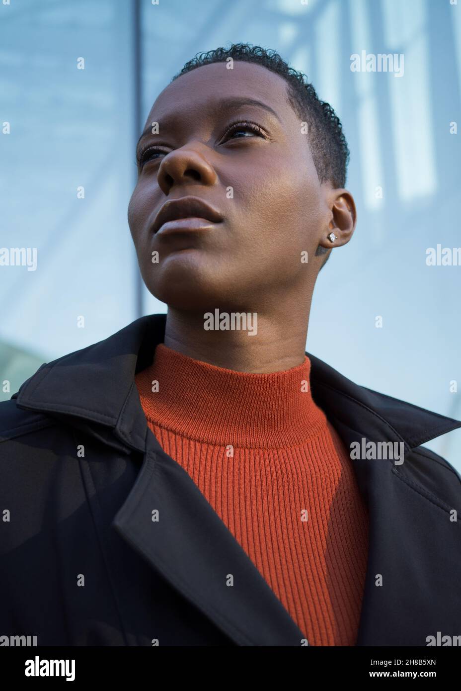 Portrait of a young woman in black coat and orange mock turtleneck shirt Stock Photo