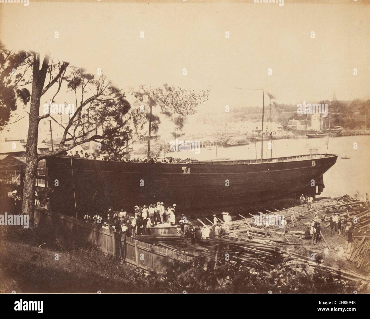 Boatbuilding, Wooloomooloo Bay, Sydney, c. 1880, vintage print, from album of views of Sydney, State Library of New SOuth Wales, DL PX 149 https://search.sl.nsw.gov.au/permalink/f/1cvjue2/ADLIB110311866  In the 1870s and 1880s Woolloomooloo Bay was known principally as a place where sailing boats could be hired, and where prawns and other bait could be bought from the boys lined along the water's edge. This picture taken around the same time, possibly by Degotardi, shows the old boat sheds, and reclaimed land around the wharves. On the left we can see a shipbuilding yard with a vessel about to Stock Photo