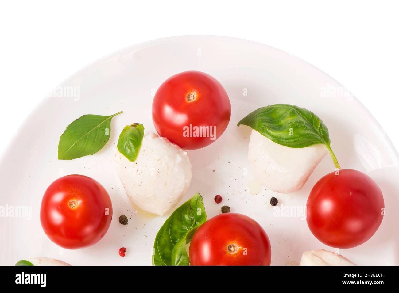 Round camembert cheese with cherry tomatoes and basil on a white plate. Stock Photo