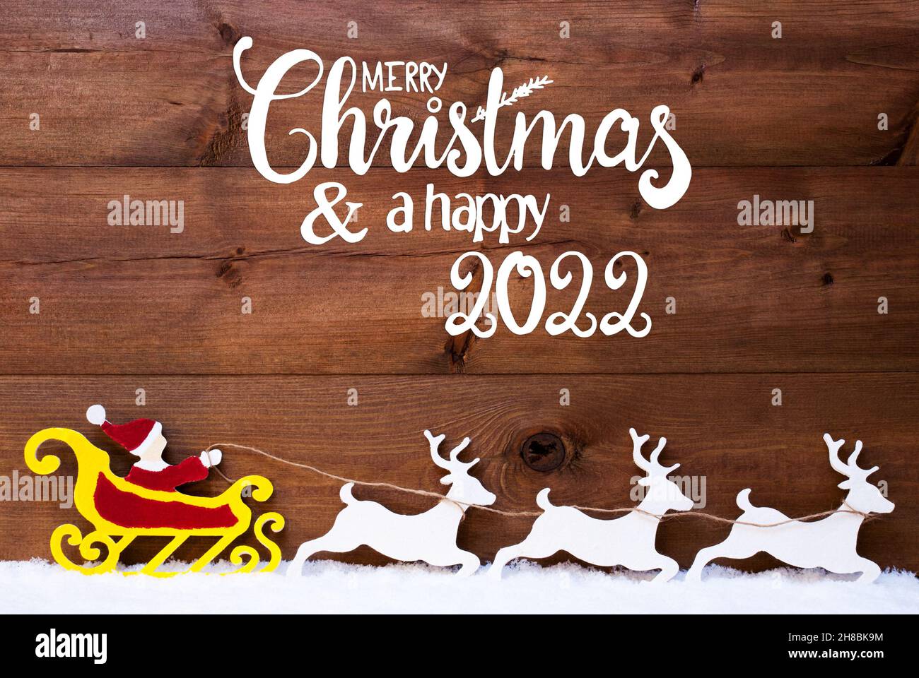 Calligraphy Merry Christmas 2022 English Calligraphy Merry Christmas And Happy 2022. Santa Claus With Sleigh  And Reindeers. Wooden Background With Snow Stock Photo - Alamy