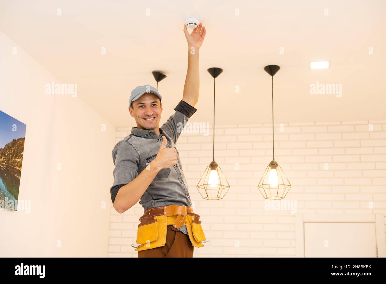 Young electrician installing smoke detector on ceiling Stock Photo