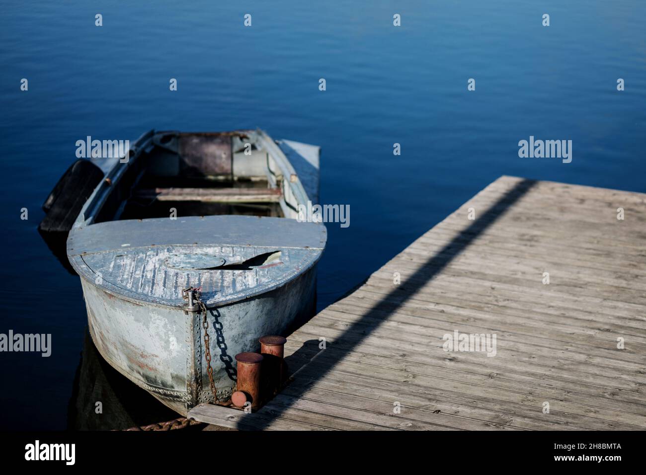 https://c8.alamy.com/comp/2H8BMTA/old-small-boat-floating-on-the-lake-near-the-pier-2H8BMTA.jpg