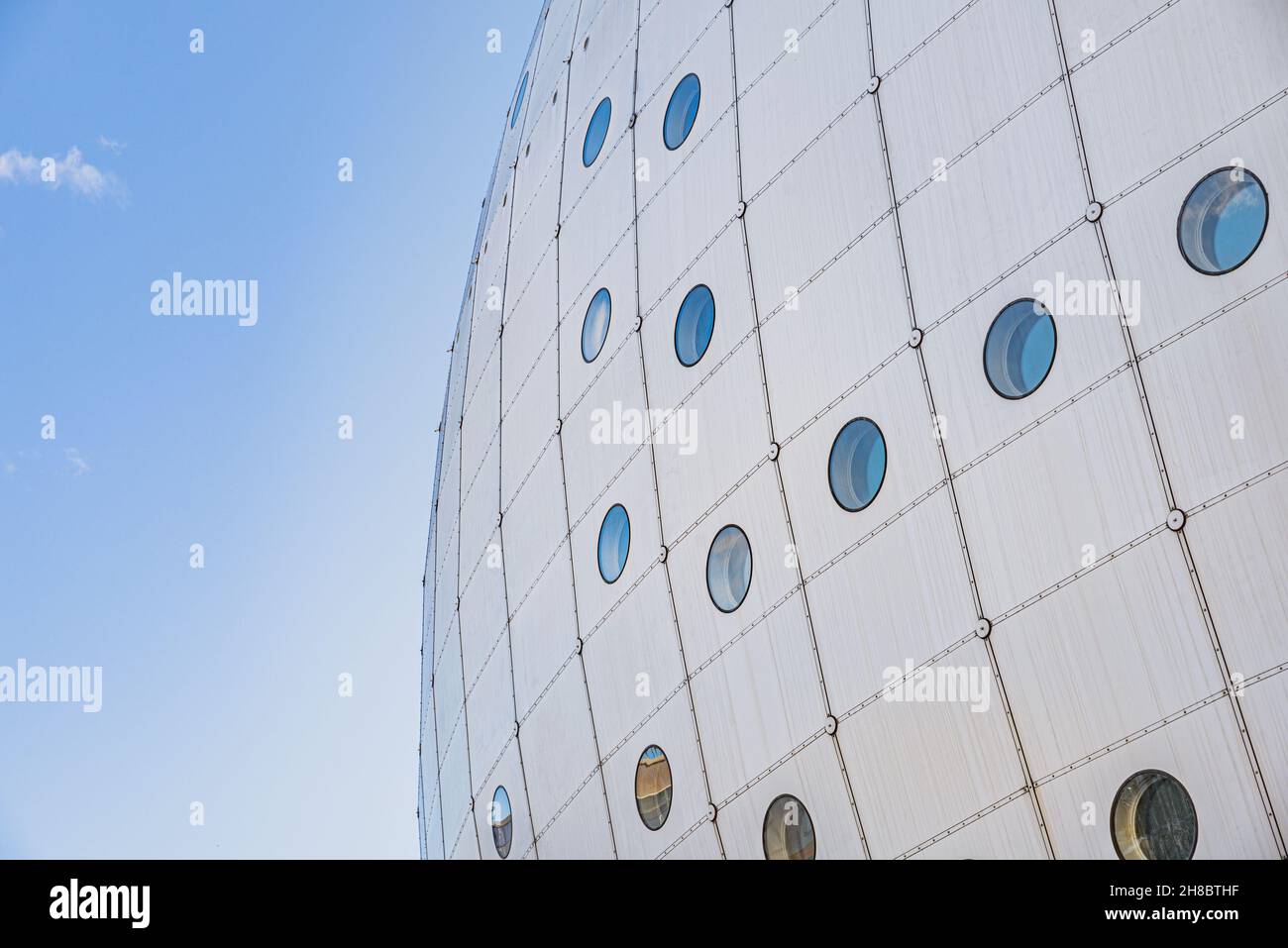 Facade detail of contemporary spherical building with circular windows or portholes shows a quirk architectural building shape. Business concept Stock Photo