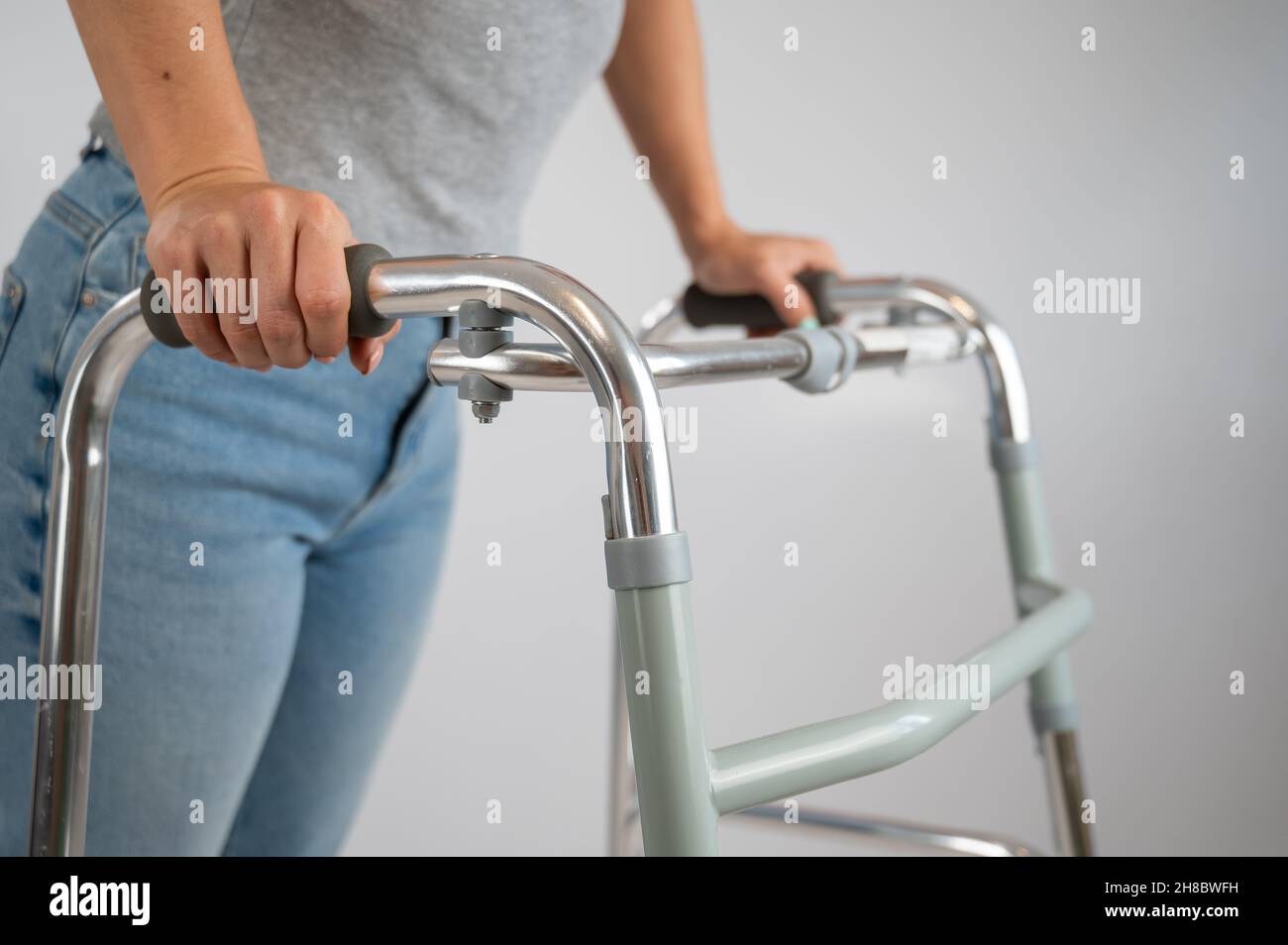 A woman is walking with a walker on a white background Stock Photo - Alamy