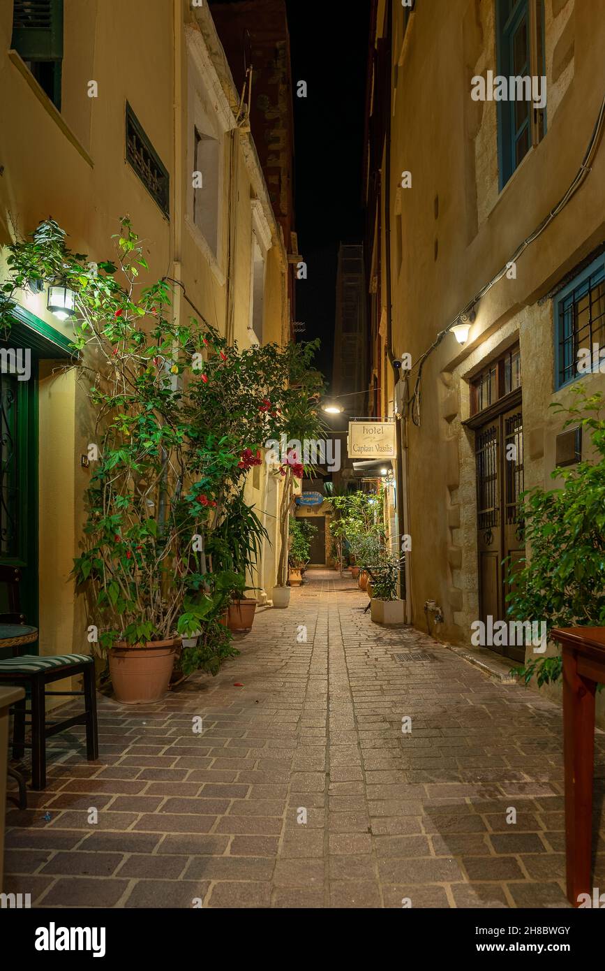 The narrow alley Sali Helidonaki with red flowers,  lit by lanternas in the old town of Chania, Crete, Greece, October 13, 2021 Stock Photo